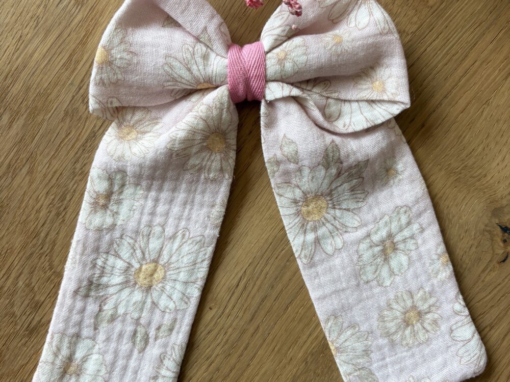 Spinka z kokardą muślinową, bardzo delikatny wzór białych stokrotek na pastelowym, różowym tle, spinka zapinana na metalową klamrę