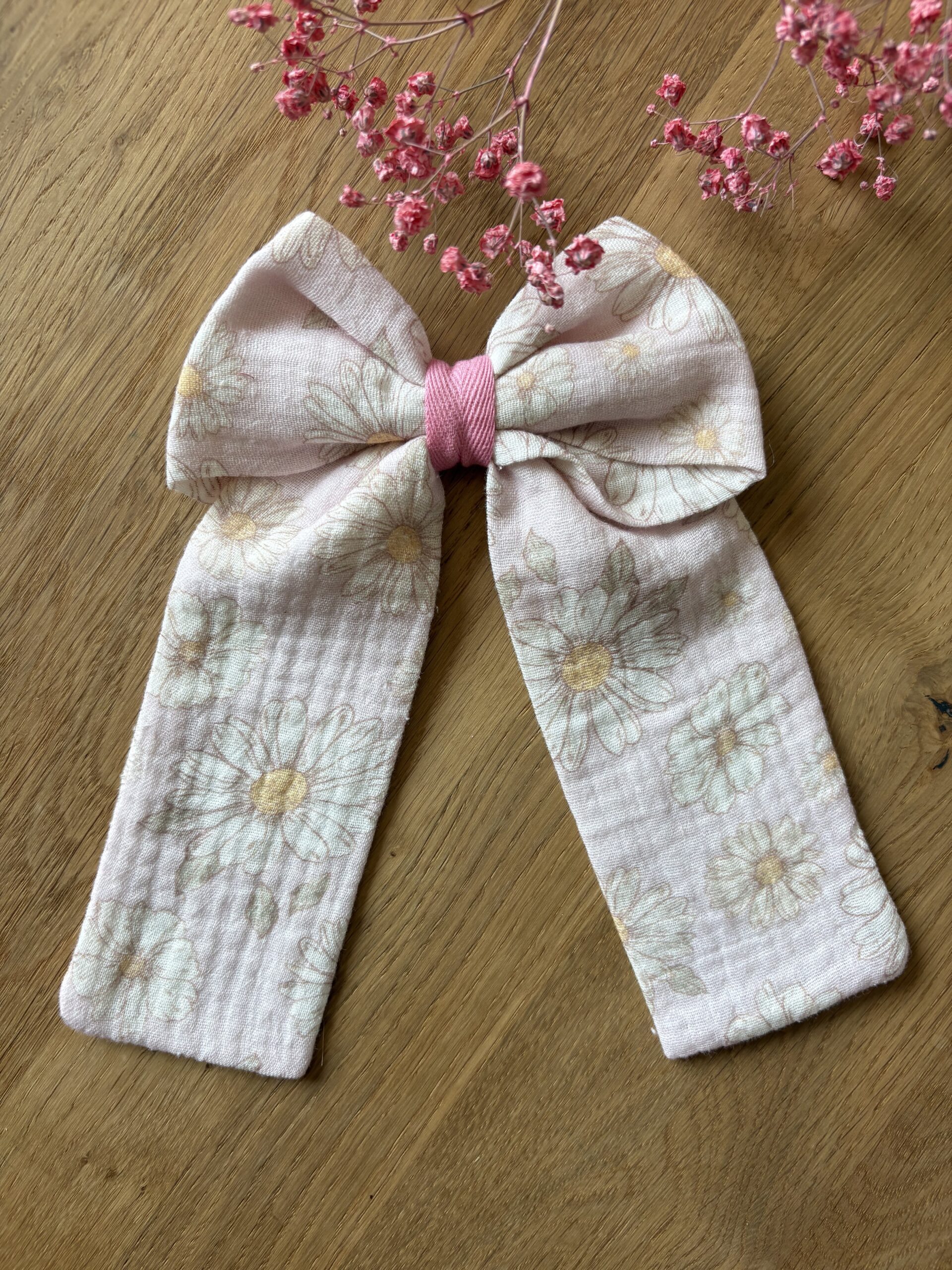 Spinka z kokardą muślinową, bardzo delikatny wzór białych stokrotek na pastelowym, różowym tle, spinka zapinana na metalową klamrę