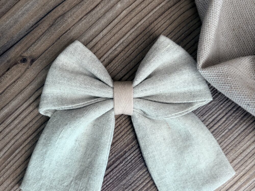 lniana kokarda, w neutralnym kolorze, zapinana na metalową klamrę